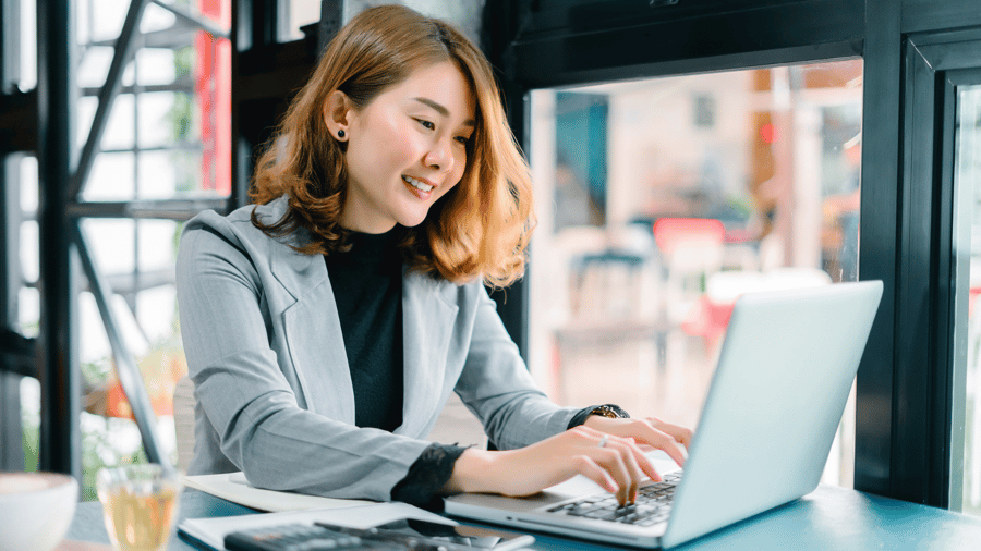 woman-typing-computer-smiling-window