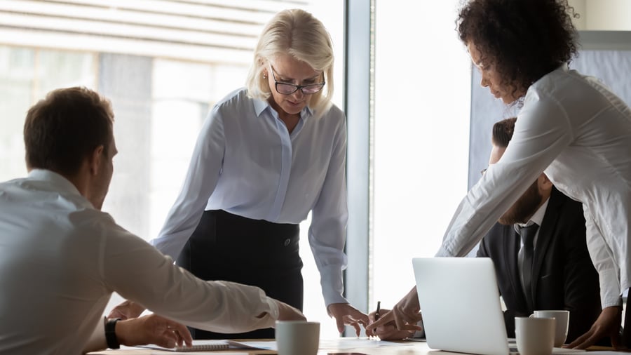 Business team meeting, older woman in glasses reading proposal